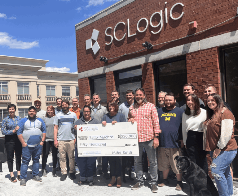 Team of SCLogic employees holding donation check for Bello Machre