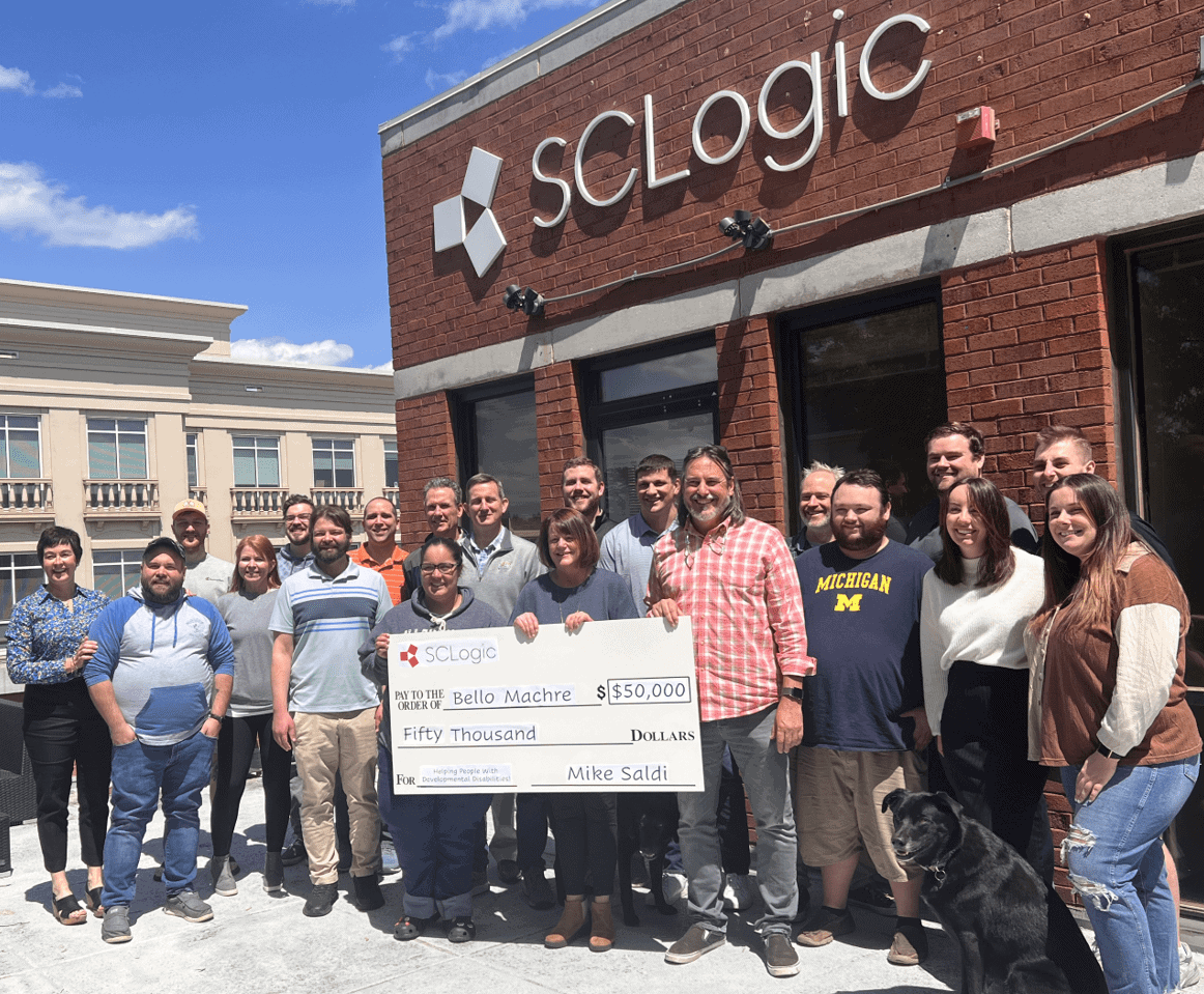 Team of SCLogic employees holding donation check for Bello Machre